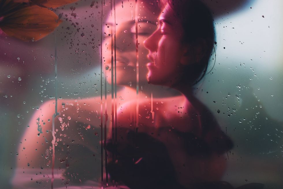 nature portrait pure soul sensual woman face blur silhouette in neon red bokeh light behind steamed glass with rain drops double exposure effect beauty wellness dreamlike freshness