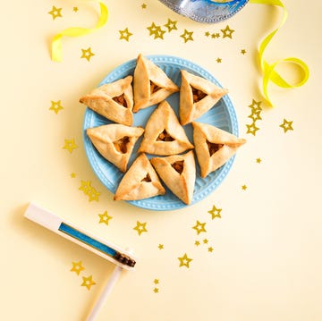 Purim celebration concept jewish purim hamantaschen homemade biscuits or cookies with mask and gragger. purim celebration concept (jewish carnival holiday) on yellow background, top view, copy spce.