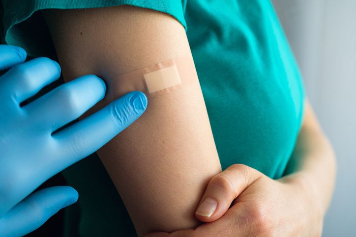 a doctor or health care professional applies a patch or adhesive bandage to a girl or young woman after vaccination or injection of medication the concept of medicine and health care, vaccination and treatment of diseases first aid