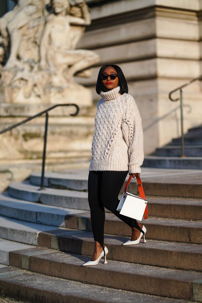 paris, france   january 09 carrole sagba aka lianose wears sunglasses, a white oversized woven knitted turtleneck wool pullover from hm, black leggingspants from acne studios, a white geometric bag from danse lente, white high heeled pointy shoes from amina muaddi, on january 09, 2021 in paris, france photo by edward berthelotgetty images