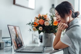 young asian woman receiving a flower bouquet while having a video call on laptop with her lover
