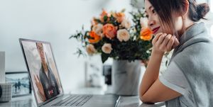 young asian woman receiving a flower bouquet while having a video call on laptop with her lover