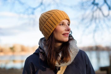A person wearing a beanie and scarf stands by a body of water