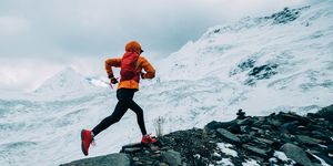 woman trail runner cross country running up to winter snow mountain top
