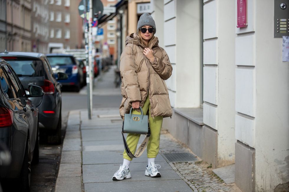 berlin, germany   january 29 sonia lyson is seen wearing white new balance sneaker, nike socks, zara jogger pants and hoody in yellow, brown puffer jacket zara, dior sunglasses, dior bag, acne beanie in grey on january 29, 2021 in berlin, germany photo by christian vieriggetty images