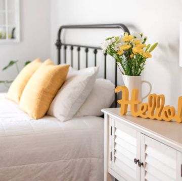 cheerful yellow hello sign and fresh flowers in a clean and bright bedroom
