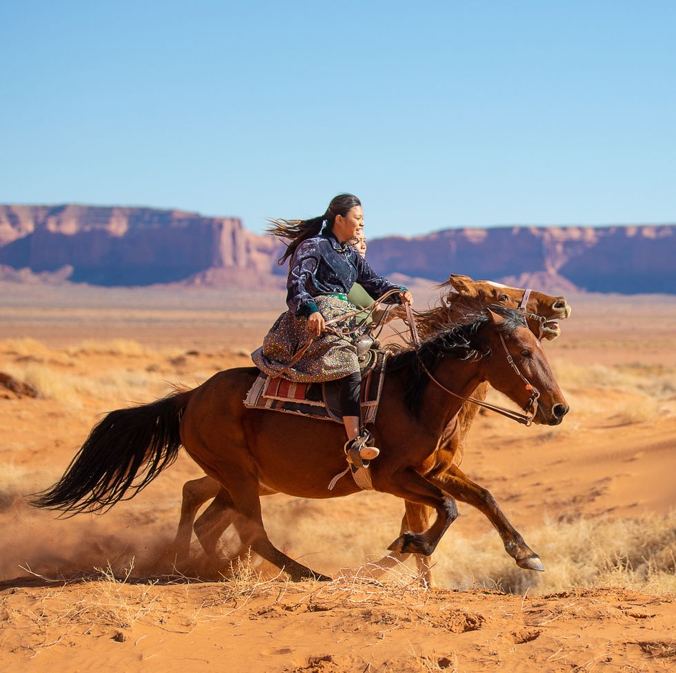 navajo brothers galloping on horses in arizona usa