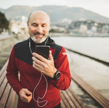 happy and positive emotions after running outdoors workout results in app on phone synchronize and listening music social distancing and online services to speak with relatives and friends active and well being lifestyle in old age handsome senior man with beard