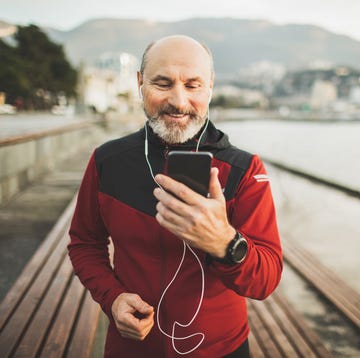 Senior adult athlete share training results online with friends by video communicating on phone happy and positive emotions after running outdoors workout results in app on phone synchronize and listening music social distancing and online services to speak with relatives and friends active and well being lifestyle in old age handsome senior man with beard