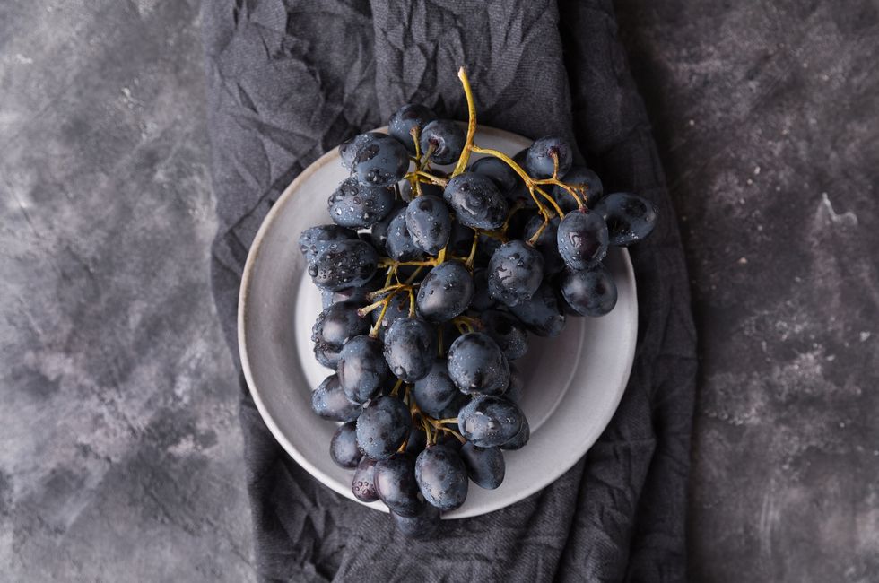 fresh ripe black grapes on dark concrete background, top view, copy space