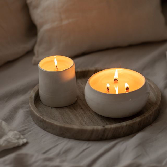 scented candles in ceramic bowls on linen bed