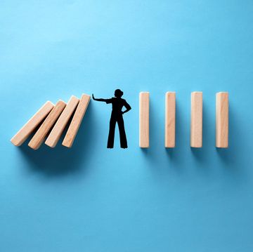 silhouette of a woman stopping wooden dominos from collapsing