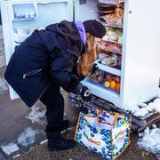 This is an image woman in snow in front of community fridge