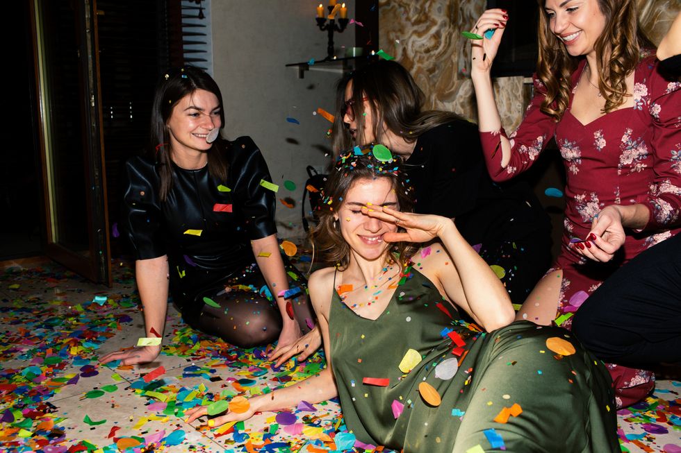 group of beautiful young people throwing colorful confetti while dancing and looking happy friends making big party in the night new years or birthday party series