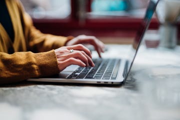 side view of female hand typing on laptop keyboard freelancer working with laptop at cafe technology and flexible working