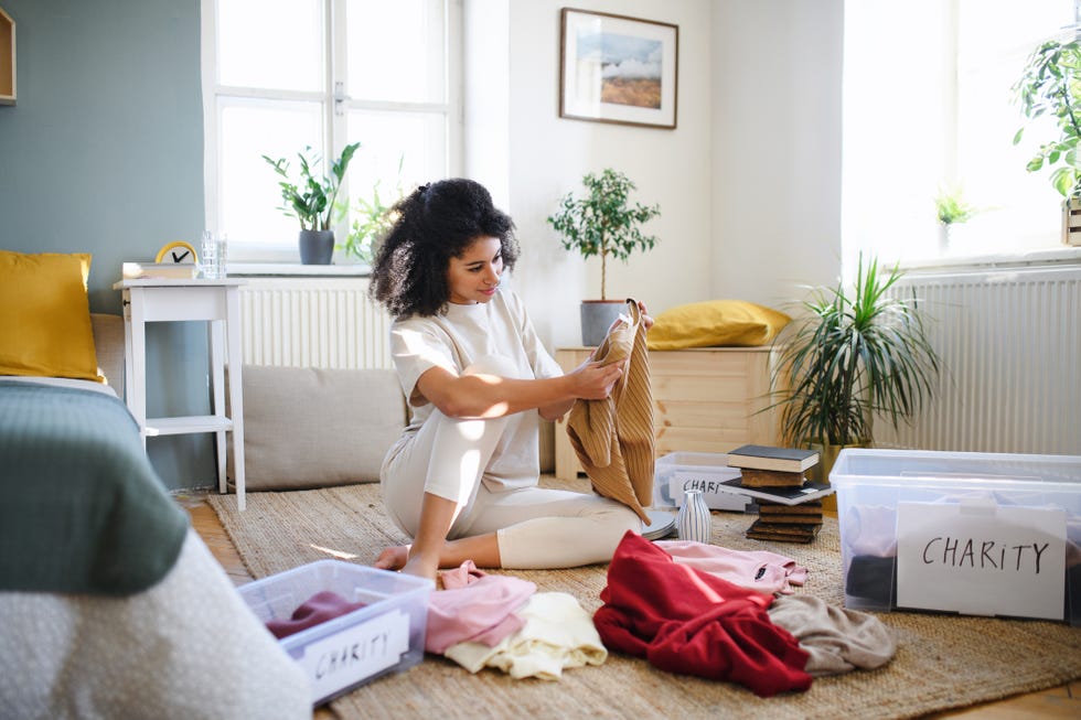 happy young woman sorting wardrobe indoors at home, charity donation concept