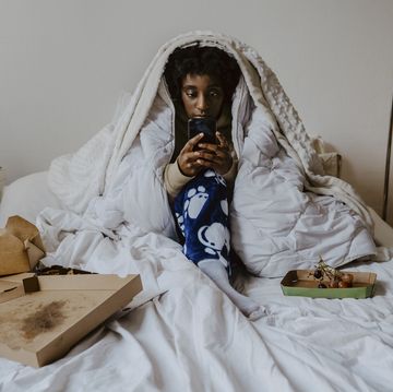 young woman using smart phone while sitting in bedroom