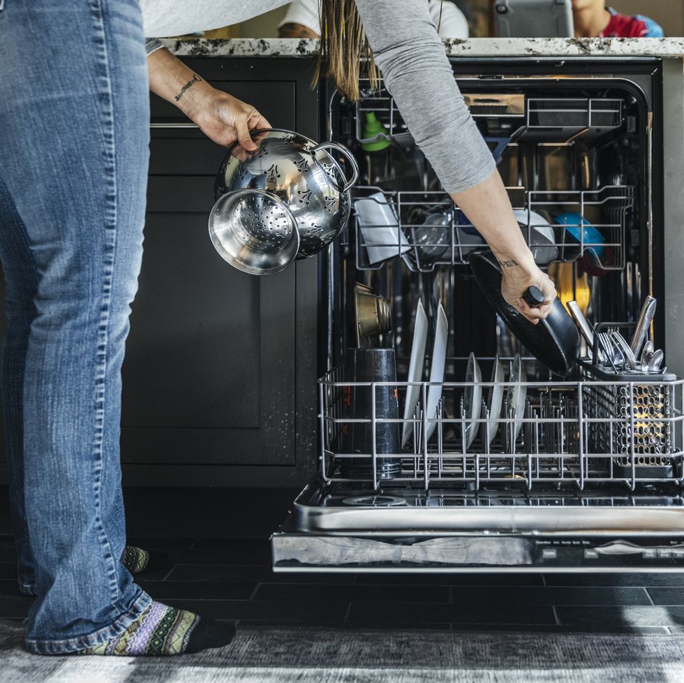 woman arranging utensils in dishwasher at home