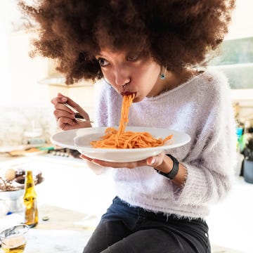 Young woman eating spaghetti a person eating a plate of food