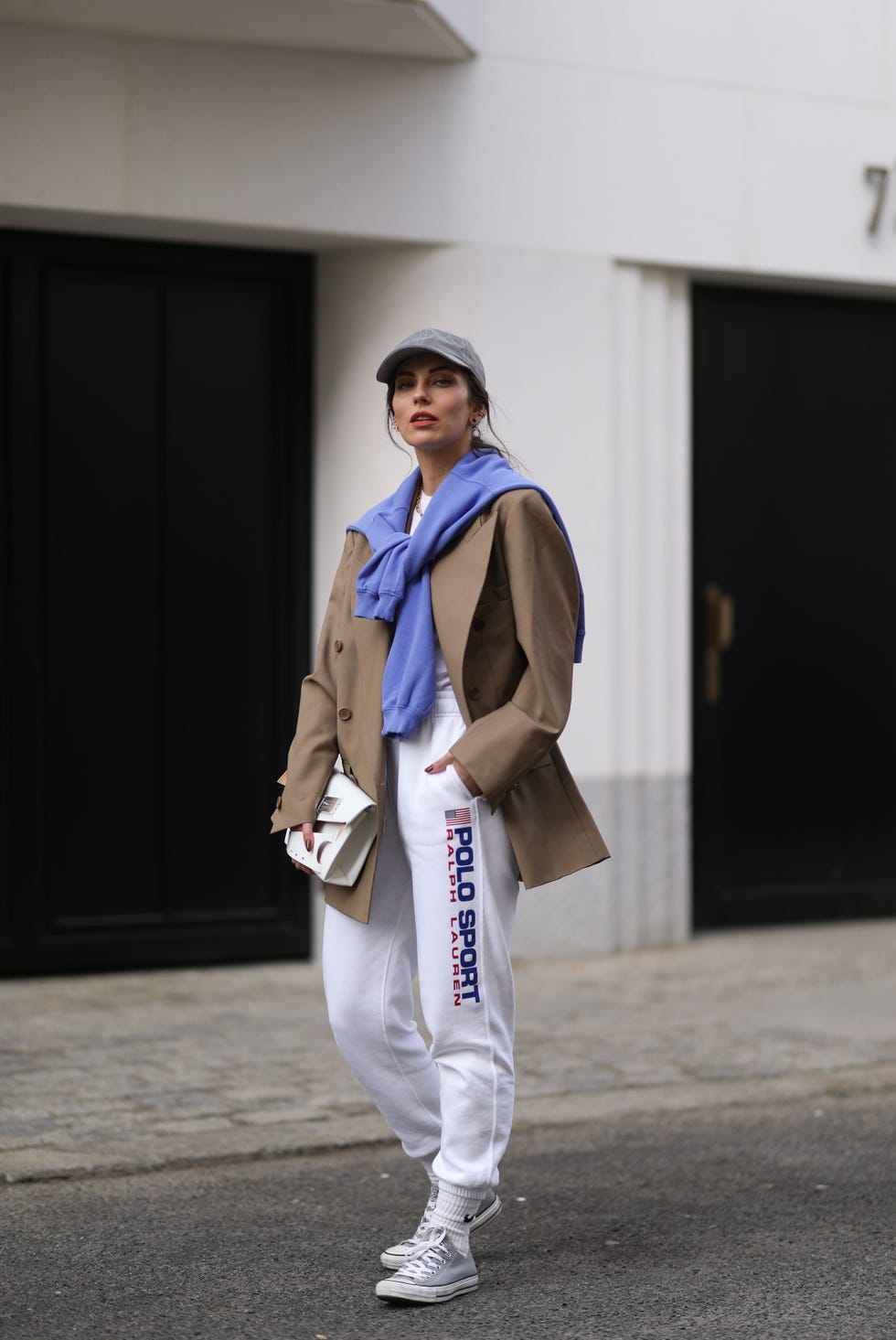 berlin, germany march 03 masha sedgwick wearing converse grey low sneaker, white nike logo socks, polo ralph lauren pants and shirt, maison margiela white bag, envelope 1976 green blazer, fila silver cap and ecoalf purple sweater on march 03, 2021 in berlin, germany photo by jeremy moellergetty images