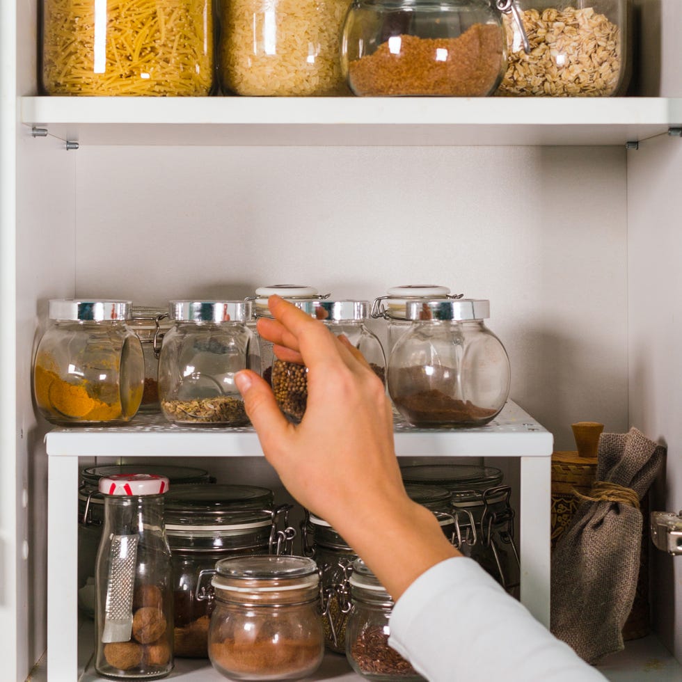 woman hand opens kitchen shelf with various cereals and seeds in glass jars on the shelves in the kitchen eco friendly kitchen, zero waste home concept