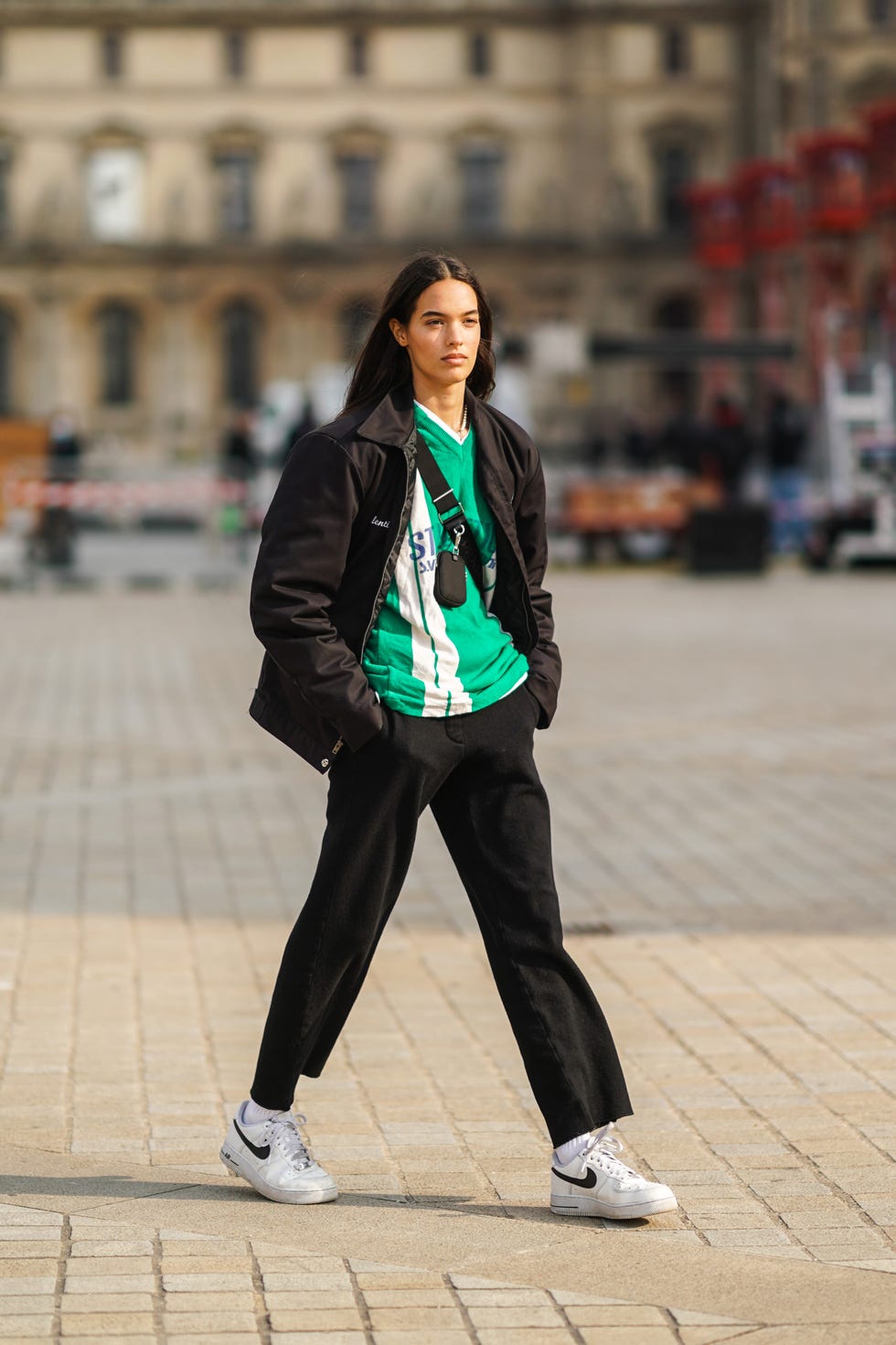 paris, france march 09 a model wears a a black jacket, a green and white stripe v neck soccer t shirt, a mini fanny pack bag crossbody, black pants, white socks, white nike sneakers, on march 09, 2021 in paris, france photo by edward berthelotgetty images