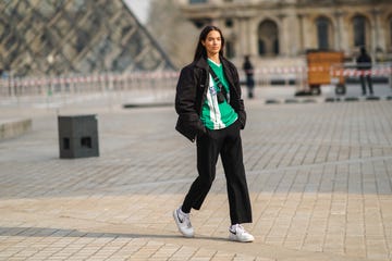 paris, france march 09 a model wears a a black jacket, a green and white stripe v neck soccer t shirt, a mini fanny pack bag crossbody, black pants, white socks, white nike sneakers, on march 09, 2021 in paris, france photo by edward berthelotgetty images