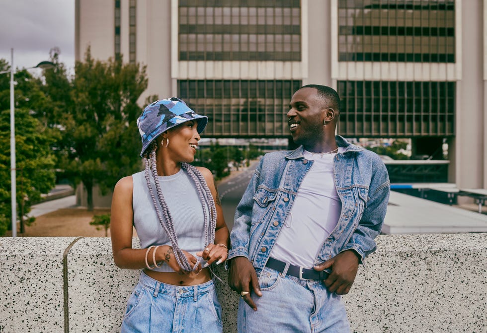 shot of a trendy young couple leaning against a wall in the city and chatting