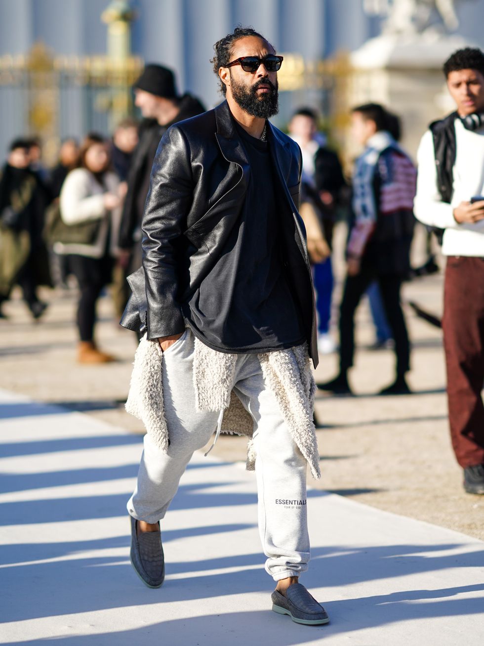 paris, france   january 16 jerry lorenzo, fear of god founder, wears sunglasses, silver chain necklace, a black wool pullover, a beige fluffy jacket, black shiny oversized leather coat, gray essentials sport pants, gray crocodile pattern leather moccasins, outside vuitton, during paris fashion week   menswear fall  winter 2020 2021 on january 16, 2020 in paris, france photo by edward berthelotgetty images