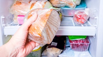 a hand putting a package of brown bread in reserve on a shelf of a home freezer, long life food storage concept