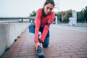 young sporty woman feeling pain in her ankle sportswoman holding her injured leg after jogging in the city