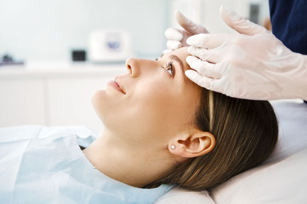cosmetologist preparing patient for facial treatments