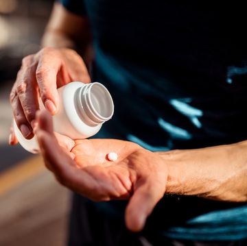 close up of human hands man holding the medicine bottle in one hand and pill in other