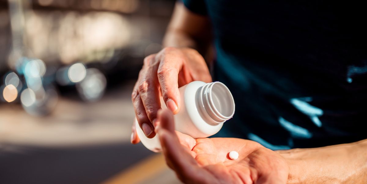 close up of human hands man holding the medicine bottle in one hand and pill in other