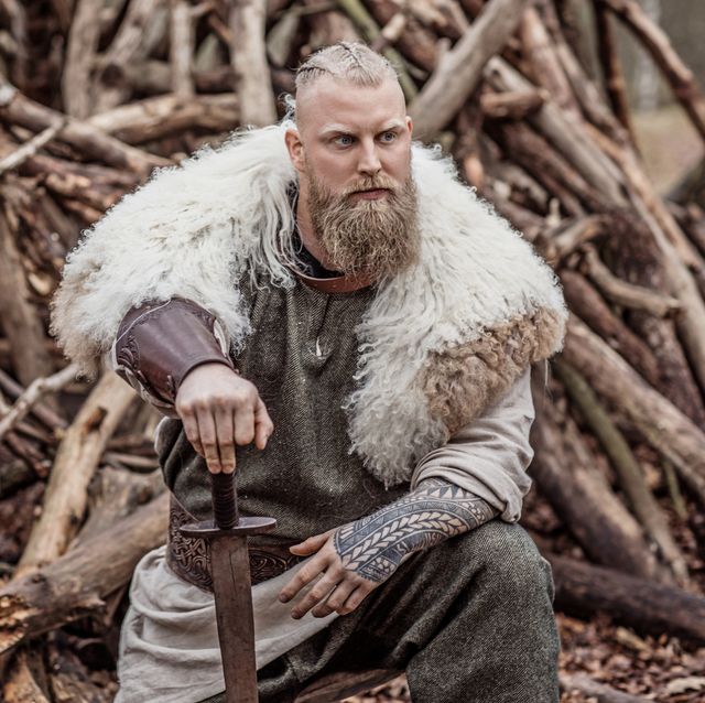 a portrait of a handsome viking warrior in an autumnal forest