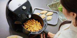 vrouw met patatjes in airfryer