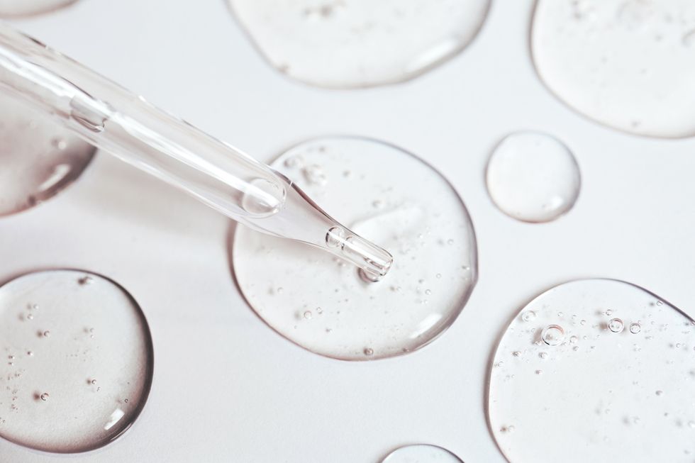 drop of gel or serum with air bubbles flow out from a pipette near other drops on a pastel white background flat lay style and extreme close up