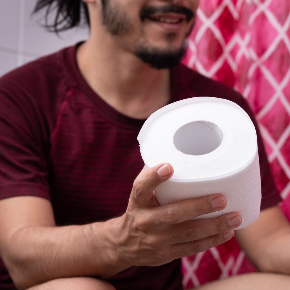 close up of a young latin man hand holding a toilet paper at the bathroom