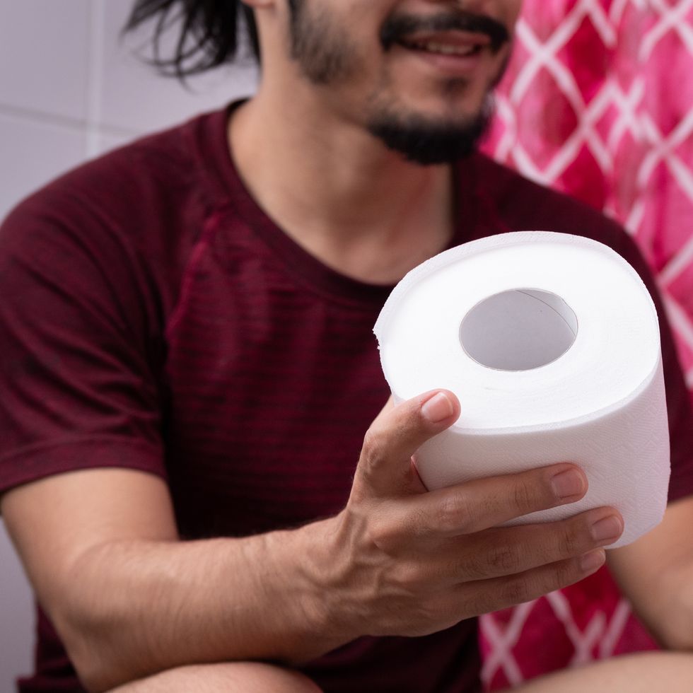 close up of a young latin man hand holding a toilet paper at the bathroom