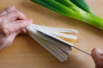woman cutting spring onion using japanese kitchen knife