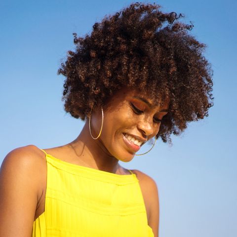 portrait of a young black woman wearing yellow dress smiling