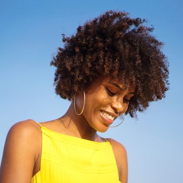 portrait of a young black woman wearing yellow dress smiling