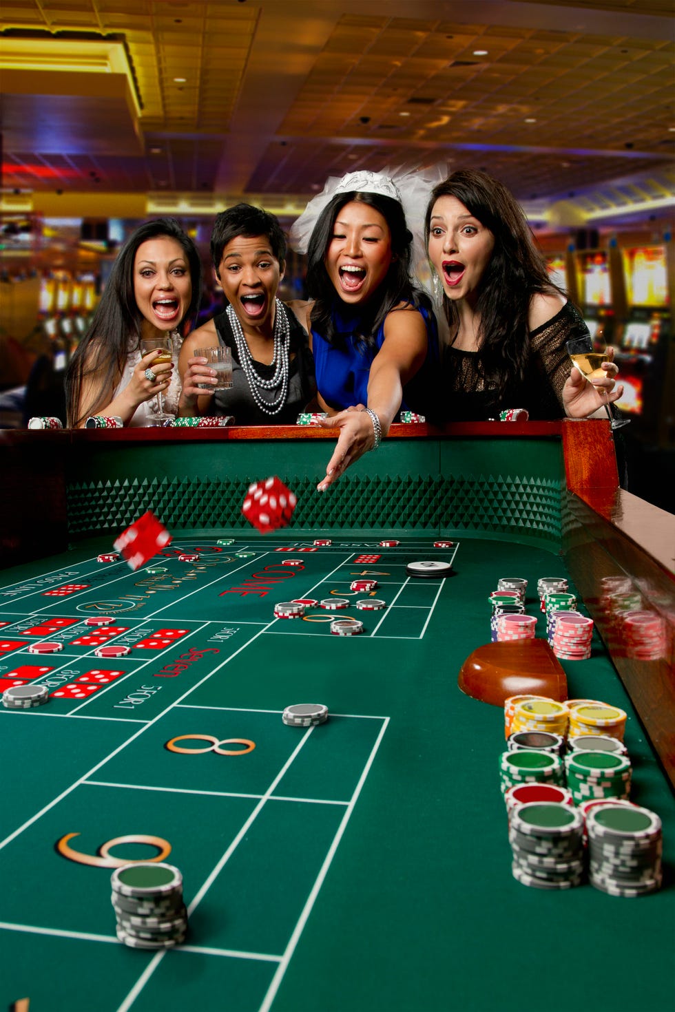 excited friends gambling at craps table in casino