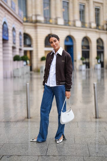 paris, france may 06 tamara kalinic wears a brown celine teddy jacket, a white shirt, blue long flared slit denim jeans pants, a white prada cleo bag, black and white pointed shoes from ysl saint laurent, on may 06, 2021 in paris, france photo by edward berthelotgetty images