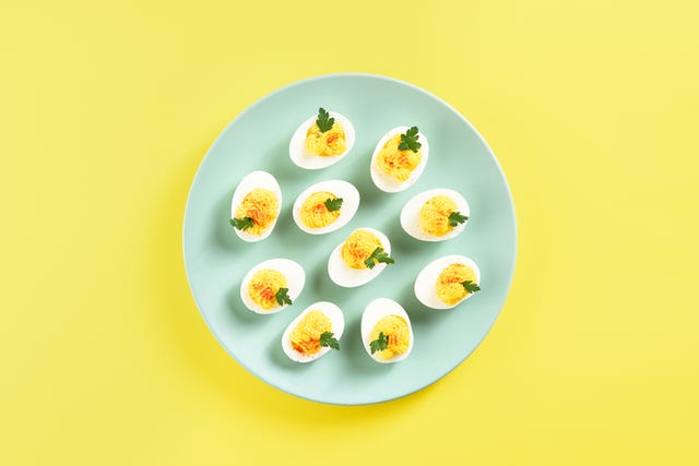 deviled eggs with paprika, mustard and mayonnaise appettizer for breakfast or lunch yellow background with free text space top view, flat lay