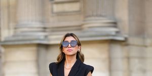 paris, france may 29 angela gonzalez wears black sunglasses, earrings, a gold chain necklace, a black shoulder off t shirt, a black sleeveless blazer jacket with epaulets shoulder pads from zara, a gold chain bracelet, black split flared suits pants from asos, brown and black leather ankle black heels boots from na kd, a brown shiny leather lancaster handbag, on may 29, 2021 in paris, france photo by edward berthelotgetty images