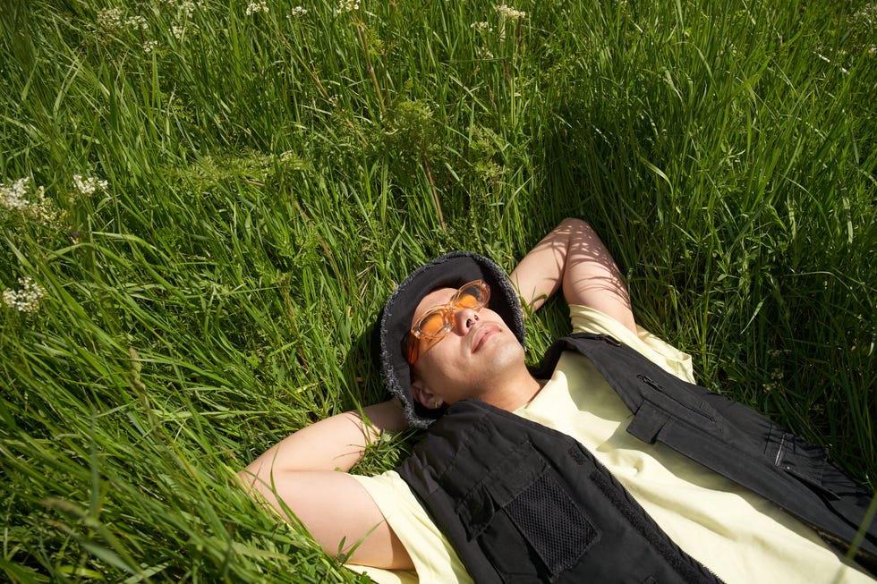 fashionable man relaxing in long grass on a spring day