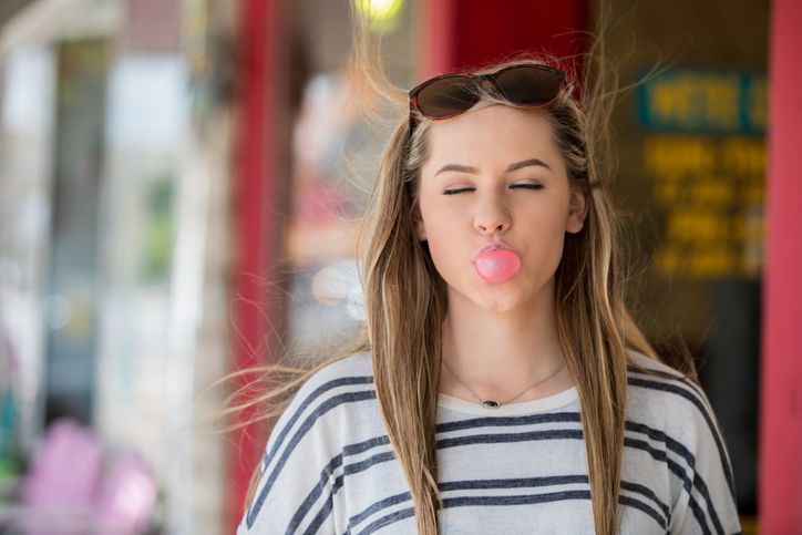 young female blowing a bubble with her bubblegum