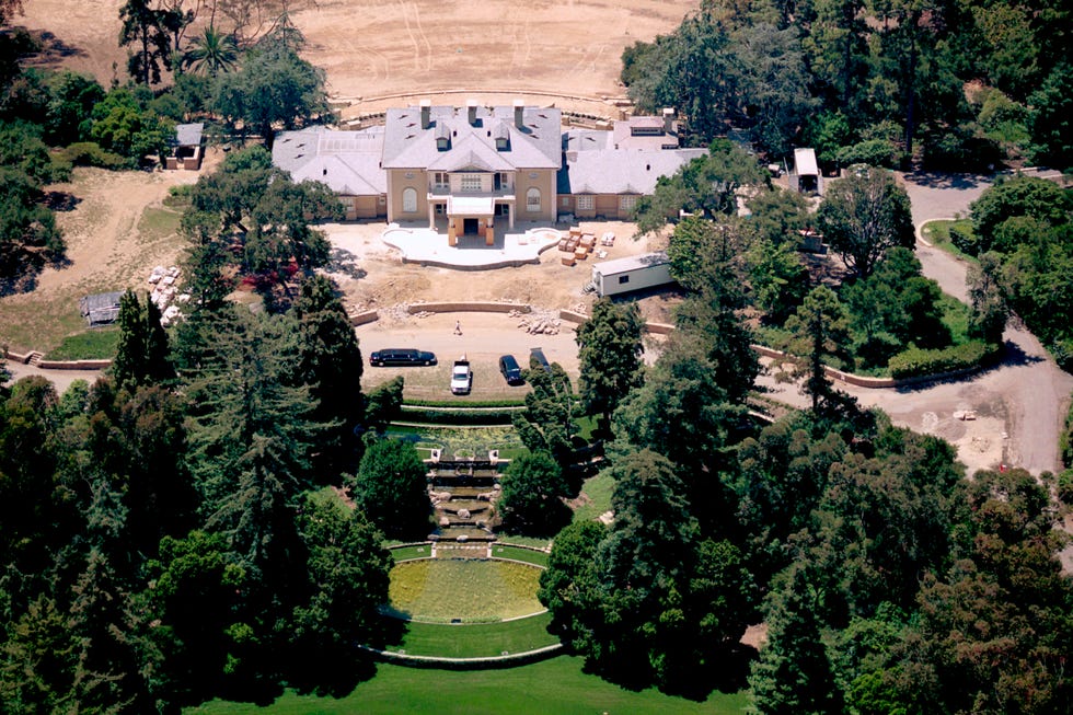 aerial view of a large mansion surrounded by greenery and a landscaped garden