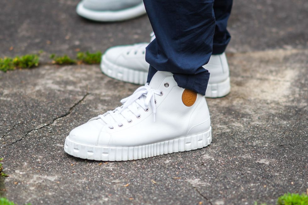 paris, france   june 26 a guest wears navy blue suit pants, white shiny leather sneakers from tommy hilfiger, outside hermes, during paris fashion week   menswear springsummer 2022, on june 26, 2021 in paris, france photo by edward berthelotgetty images